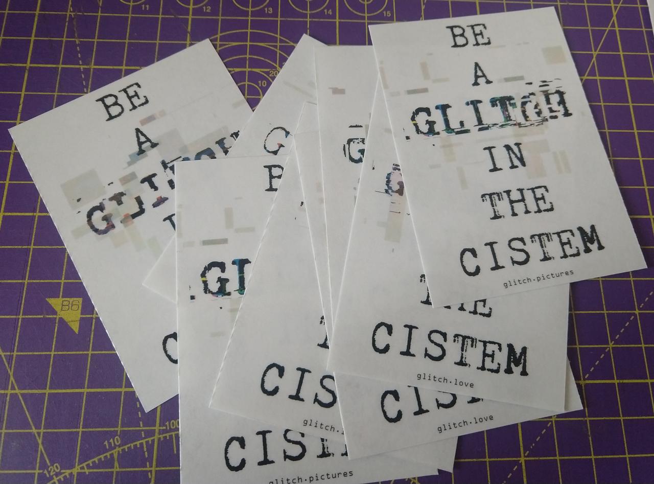 A loose pile of stickers with "Be a glitch in the Cistem" on it.